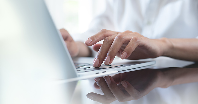 Fingers typing on laptop keyboard.